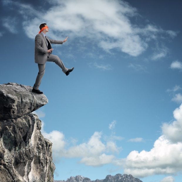 © Brian Jackson / Adobe Stock - Businessman in a blindfold stepping off a cliff ledge concept for risk, challenge, conquering adversity or ignorance